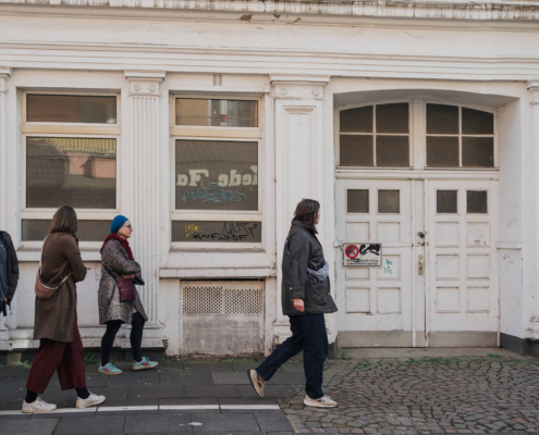 Menschen laufen auf Straße, Altbaugebäude im Hintergrund